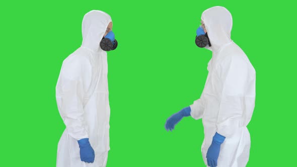 Doctors or Scientists in Hazamat Suits Meet and Shake Hands on a Green Screen, Chroma Key.