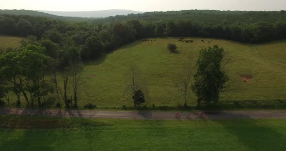 Aerial views of family bicycling along pastoral country roads.