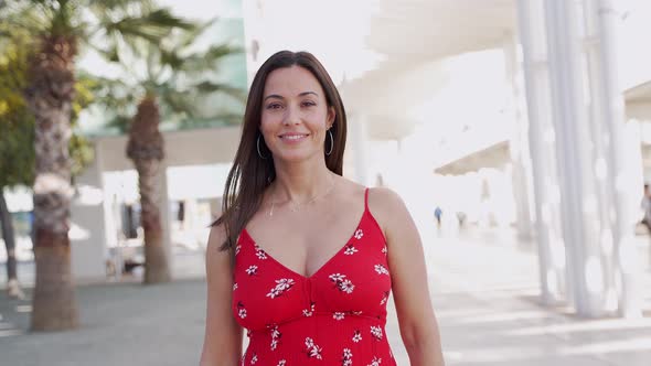 Smiling Woman in Trendy Dress Walking on Street and Looking at Camera