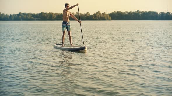 Tourist Floating Sup Board On Vacation.Tourist Floating Standup Paddle Board.Strong Man Swim Surfing