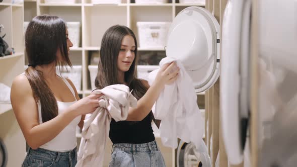 Mother Daughter Loading Clothes Into Washing Machine Self Service Laundry