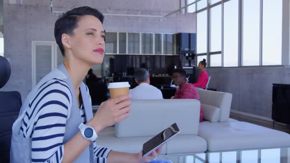 Beautiful Caucasian Businesswoman using digital tablet while drinking coffee in modern office 4k