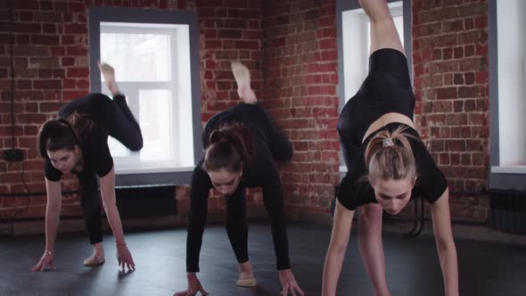 Stretching Three Young Flexible Women Leaning on Their Hands and Raising One Leg Up Then Raising