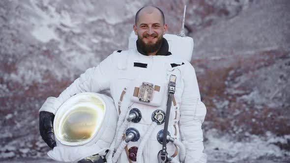 Astronaut with a Helmet in His Hand Smiles Broadly and Looks at the Camera