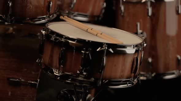 Pair of drumsticks on a snare drum. Camera slowly rotates around the kit. 4KHD