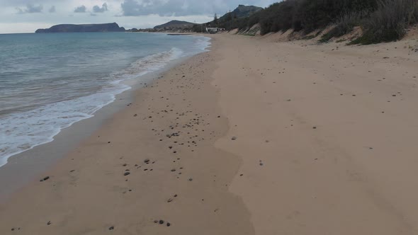 Low-level drone flight along empty Porto Santo beach, Portugal. Aerial forward