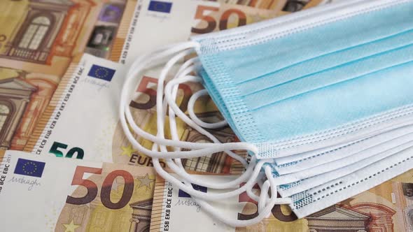 A stack of medical masks falls on Euro banknotes in slow motion