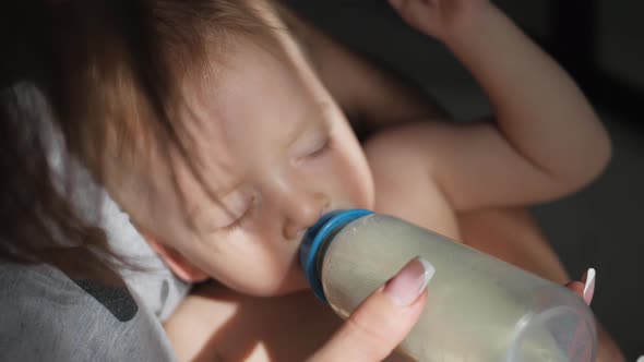 Beautiful Mom Feeds Infant Son From Milk Bottle