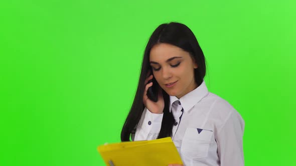 Attractive Businesswoman Talking on the Phone, Holding Clipboard