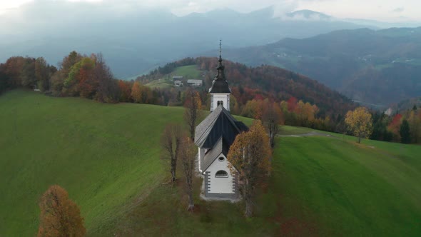 Amazing Beautiful Aerial View of the Hills, Colorful Forest and the Sv Sobota Church. Slovenia