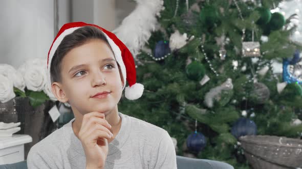 Adorable Young Boy in Santa Claus Hat Looking Away Thoughtfully