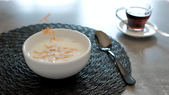 Breakfast with whole wheat cereal and corn with plum falling into the bowl. Slow motion.