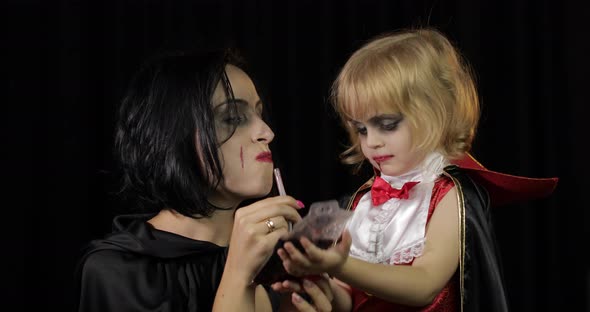 Woman and Child Dracula. Halloween Vampire Make-up. Kid with Blood on Her Face