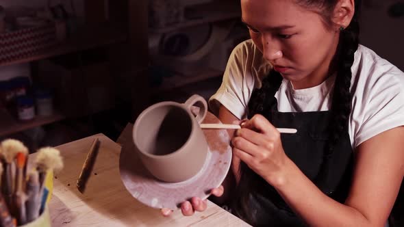 Pottery in the Art Studio Asian Woman Holding a Cup on the Plate and Smearing Clay on the Joint on