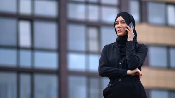 Confident Modern Muslim Woman Talking Smartphone Outdoor at Glass Building Exterior Summer City