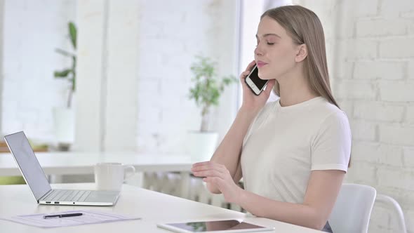 Happy Young Woman Talking on Smart Phone in Office