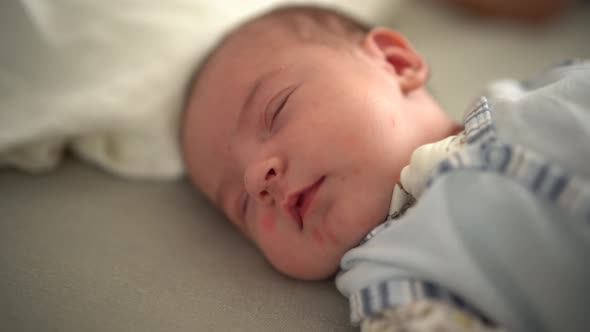 Newborn Sleeps on the Bed and Shudders in Sleep