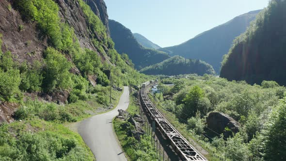 Cargo train is passing deep down in green lush valley Dalevaagen - Static aerial view Norway Bergens