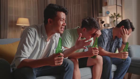 Three Asian Males Cheering And Watching Football Game On Tv And Disappointed At Home