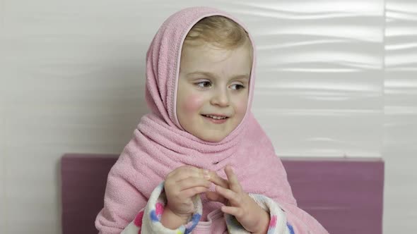 Little Girl with Wet Hair Is Hiding in Pink Towel. Smiles After Bathing