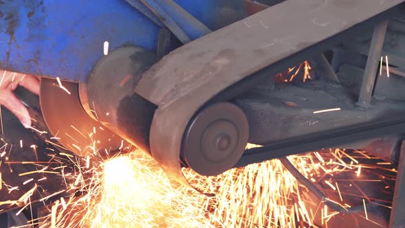 Man cuts metal with a circular saw, sparks flying from the saw blade