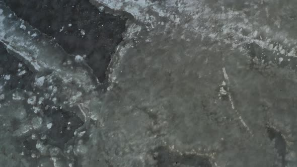 Aerial above frozen lake, ice sheets on top of water, winter season