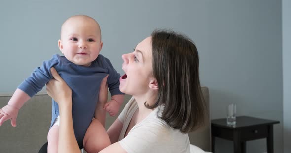 Beautiful Young Mother Holding Little Son in Arms, Woman and Child Laughing