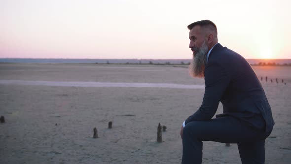 Handsome Bearded Mature Man in Suit Posing Outdoors on Beach During Sunset Slow Motion