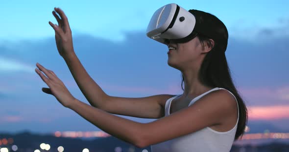 Woman watching on virtual reality device at sunset time 