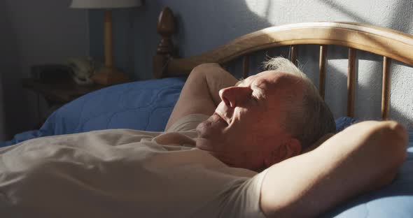 Senior man lying on bed at home