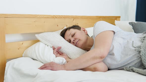 Mature Woman Falls Asleep in a Cozy Bed