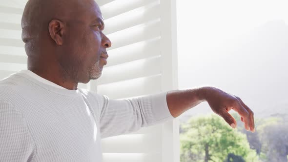 Thoughtful african american senior man looking outside window