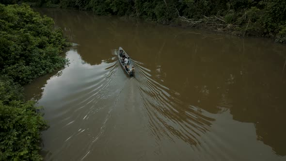 Amazon Rainforest River With Indigenous Boat Sailing Across Dense Woodland. Aerial Shot