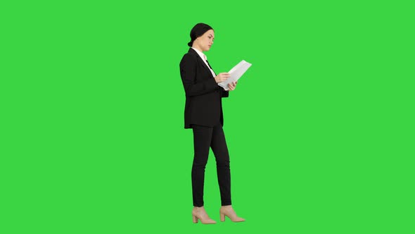 Serious Brunette Businesswoman Reading Documents on a Green Screen, Chroma Key.