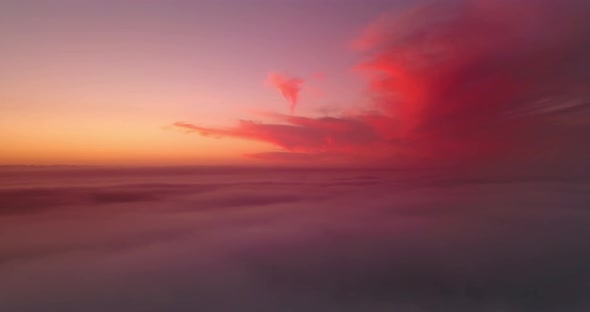 Dramatic golden red evening vanilla sky above the clouds in an ocean of sky. Aerial wide panoramic d