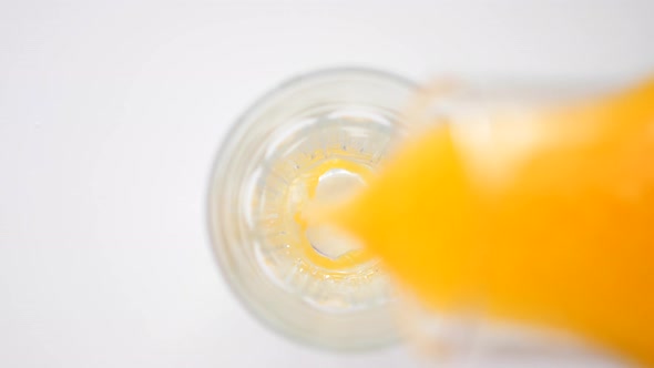 Pouring Fresh Orange Juice In Glass. Closeup.