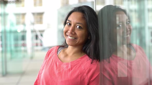 Woman leaning against window, smiling, portrait