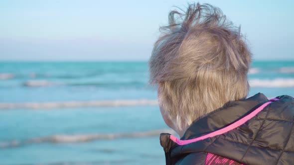 Elderly Woman Enjoys Rolling Sea Waves Standing on Beach