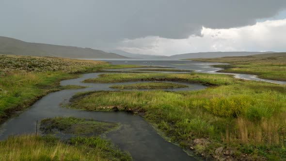 Time lapse of dramatic storm blowing over meadow with river