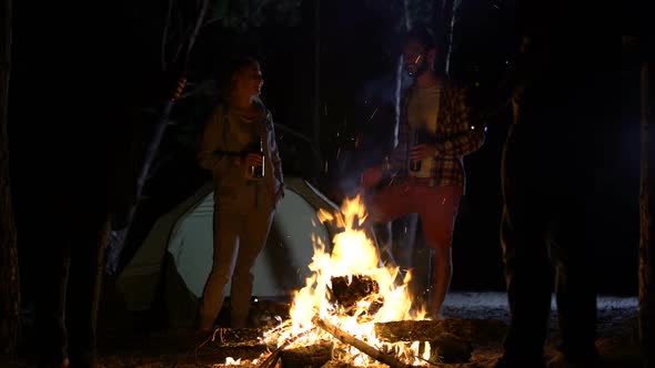 Smiling Campers Standing Around Bonfire With Beer Bottles, Having Great Time