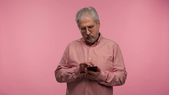 Portrait of an Elderly Man with Glasses Texting on His Phone