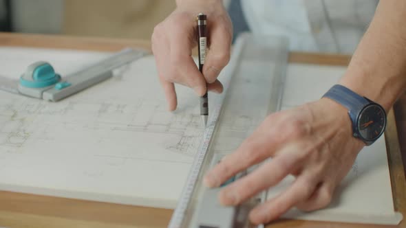 Engineer Draws Buildings on the Table Using a Pencil and Ruler