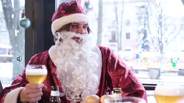 Friends in Santa Claus Costumes are Having Fun at a New Year's Party Drinking Beer in a Pub