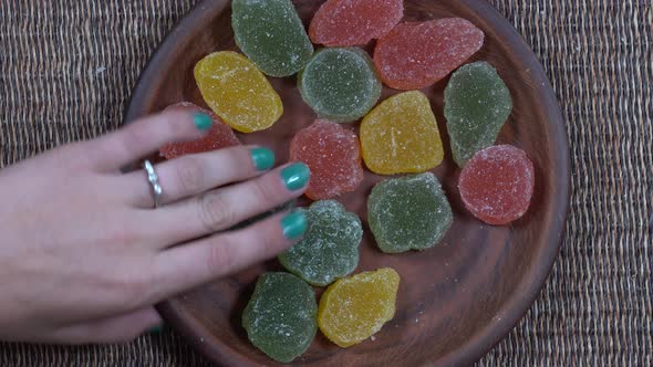 Plate full of colorful marmalade being snatched up by hungry children, closeup