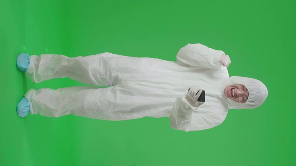Asian Man Wear Protective Uniform Ppe And Use Mobile Phone Then Celebrating In Green Screen Studio