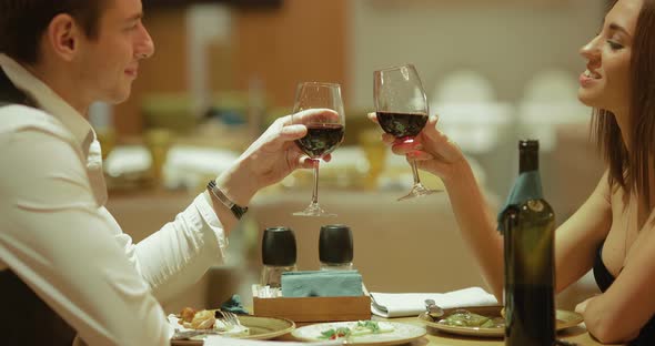 Restaurant Table, Dishes, Bottle of Wine and Glasses. Man and a Woman Check Their Glasses of Wine