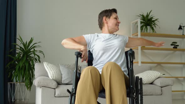 Mature 50 Yers Woman is Spreading Her Arms in Different Sides in Wheelchair