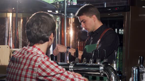 Cheerful Bartender Pouring Beer for His Customer