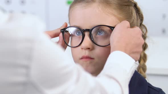 Small Schoolgirl in Eyeglasses Looking in Mirror Unhappy With Appearance, Optics