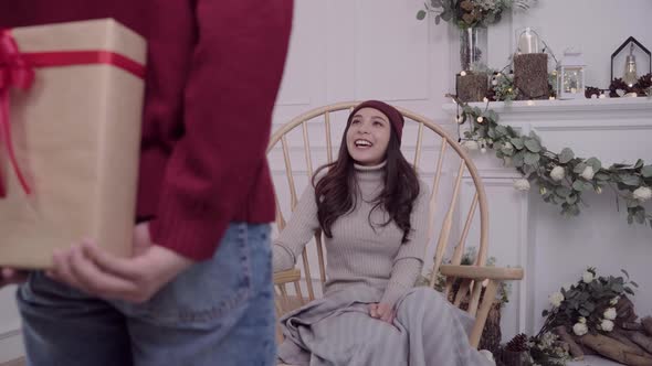Asian woman sitting on a chair wrapped in grey blanket Christmas festival getting a gift from her.